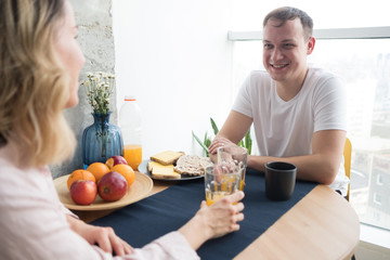 Portrait of a pretty young couple in love having tasty breakfast while sitting at the table in a kitchen