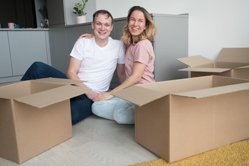 Happy couple is having fun with cardboard boxes in new house at moving day..