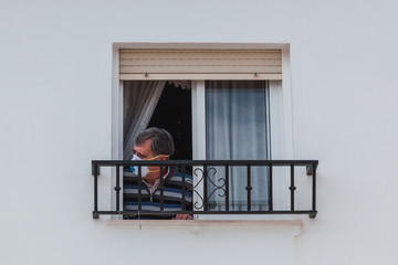 Man with a mask confined in quarantine to prevent coronavirus spread to the window.