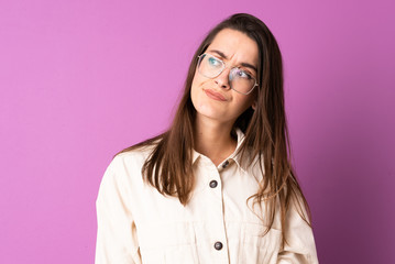 Young woman over isolated purple background making doubts gesture looking side