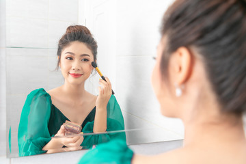 Young beautiful woman happy and making make-up near mirror in room.