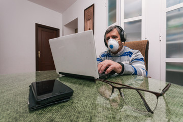 Senior man using a computer at home. Telecommuting during quarantine. Communication with family...