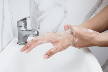 Young man washing hands over sink in bathroom, closeup, Corona virus or Covid-19 prevention, hygiene to stop.