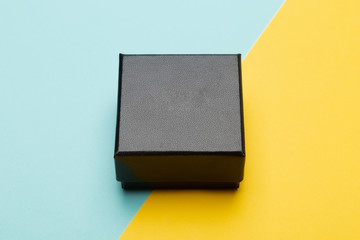 Mini black box product packaging isolated on yellow half blue background.