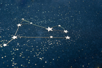 Aries zodiac sign on the starry sky close up. Application from star confetti and glitter black...