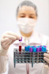 Scientist, nurse or doctor with mask and gloves holding a rake of tubes with medical analysis,...