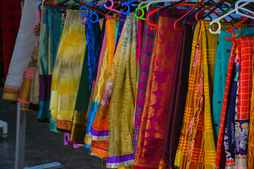 Collection of colorful sarees hanging in hangers in Indian shop