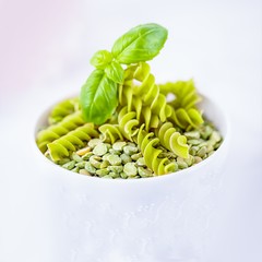 Gluten free green pea fusilli pasta and dry split light green peas on a white background, copy space