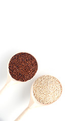 in wooden spoons on a white background are the seeds of white and red quinoa
