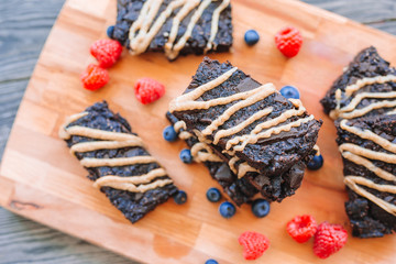 Obraz na płótnie Canvas Chocolate nut brownie cake decorated with strawberries and blueberry