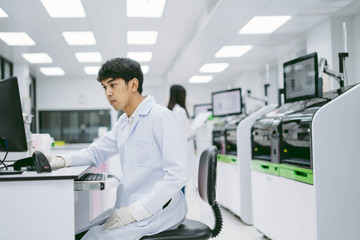 young male scientist looking results from automation blood analyzer report in computer and young...