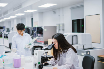 Two  medical  scientist working in Medical laboratory , young female scientist looking at microscope. select focus in young  female scientist