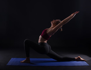 Fototapeta na wymiar Photo of young sport woman doing yoga on mat over dark background