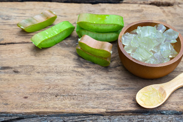 Fresh aloe vera stem slices and gel on wooden table, skin therapy concept