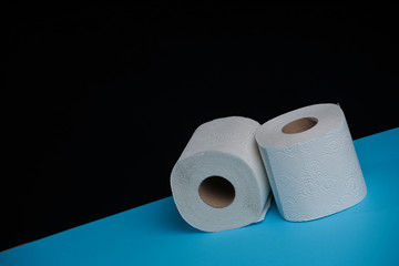 Toilet paper roll on a black blue background. Cheap toilet wipes for hygiene purposes. Soft hygienic paper.