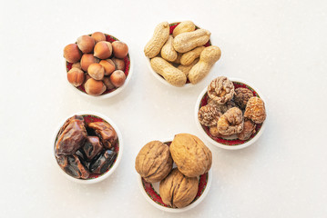 Healthy snacks nuts and dried fruits.  Top view of bowls on white table.