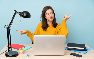 Student girl studying in her house isolated on blue background pointing finger to the laterals and happy