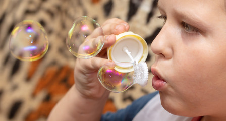The boy blows up soap bubbles