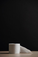 A soft hygienic toilet paper on wooden table on black background