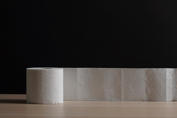 A soft hygienic toilet paper on wooden table on black background