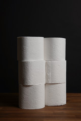 Many toilet paper rolls piled in a heap. Soft hygienic paper. Wooden table on black background.