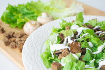 Obraz na płótnie Canvas Vegetarian version of classic Caesar salad with mushrooms instead of chicken, croutons, lettuce, parmesan cheese and dressing sauce