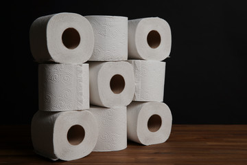Many toilet paper rolls piled in a heap. Soft hygienic paper. Wooden table on black background.