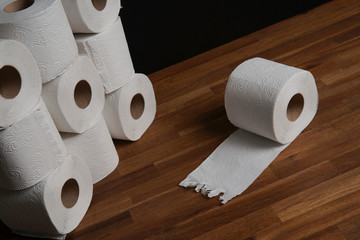 Many toilet paper rolls piled in a heap. Soft hygienic paper. Wooden table on black background.