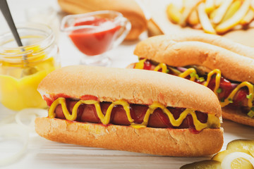 Hot dogs, fries potato and sauces on white wooden background