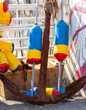 Old rusty anchor with colorful obster buoys