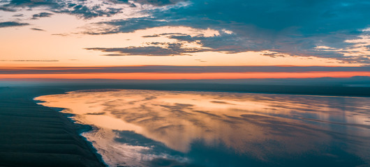 Lake at sunset from above, a beautiful pink sky with clouds reflected in the water. The salt lake Manych-Gudilo, Russia.