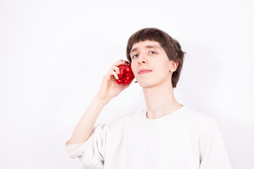 The young handsome man holds paprika like a smartphone. This situation looks like a normal phone talk, but this is only a symbolic picture. It can be called quasi phone talk.