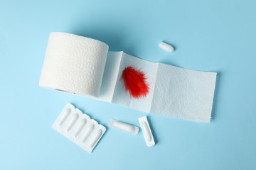 Toilet paper, feather and candles on blue background. Hemorrhoids