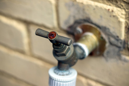 Rusty garden water tap on wall