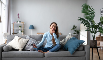 Happy woman with smartphone in casual wear on the couch.