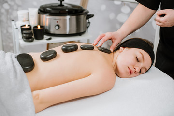 Obraz na płótnie Canvas Beautiful young woman having hot stone massage at spa