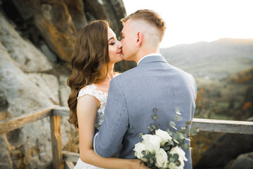 Beautiful bride and groom embracing and kissing on their wedding day outdoors