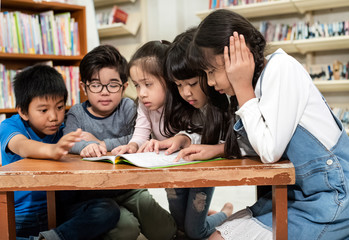 Fototapeta premium Group of children reading book togeher,with interested feeling,at library