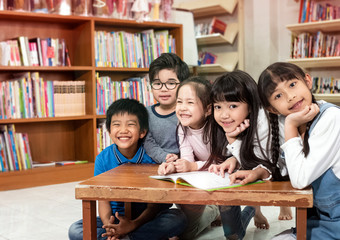 Group of children reading book together with happy feeling,at library,Lens flare effect,blurry light around