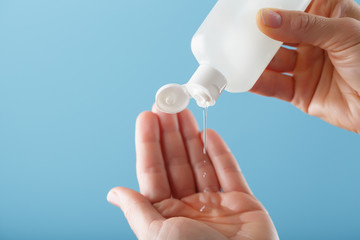 A bottle of Disinfectant gel in your hands on a blue background. Antiseptic treatment of hands from bacteria Sanitizer.