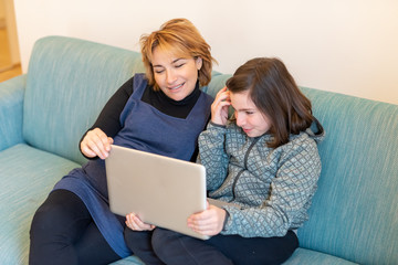 Caring mother helps her daughter to do her homework during quarantine, home schooling using modern technology, use of laptop for home instruction