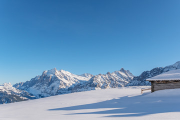 Verschneite Winterlandschaft mit einsamer Berghütte in den Schweizer Bergen - 335038171