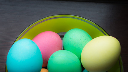 Close up different colored eggs on the bowl on black background for Easter concept.