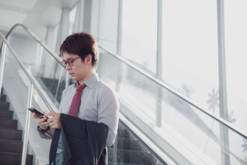 Handsome confident businessman talking something on smart phone and walking inside in airport.