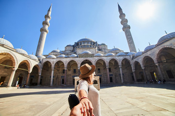 Follow me. A woman tourist in a hat leads her friend to the Turkish mosque Suleymaniye, Istanbul,...