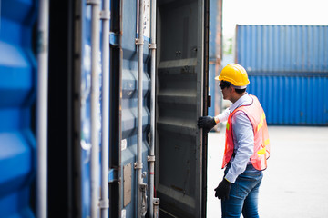 Young Asian man worker foreman open the door of shipping Containers at commercial shipping dock...
