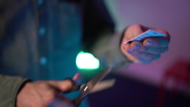 Close up shot. Man hands cuts up his credit card.