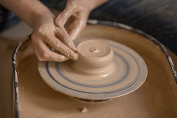 Workflow of a woman working behind a pottery wheel in an art workshop. Unknown master creates a jug. Focus only on the hands. Small business, talent, invention, inspiration concept.