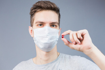 Young man in a mask with a red pill in his hand