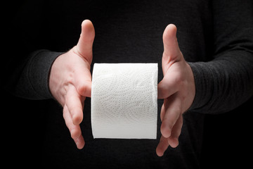 A man twists a roll of toilet paper on his fingers. The concept of indigestion, diarrhea,...
